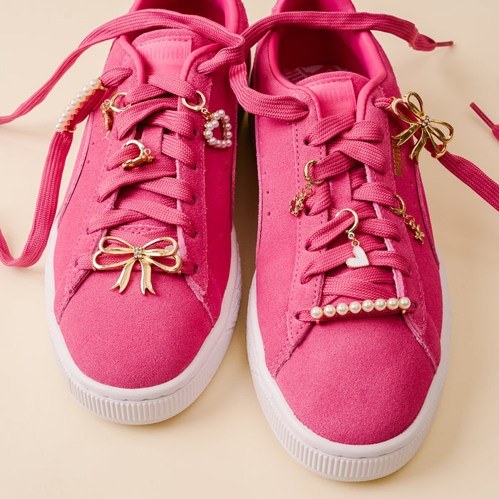 Add a fun twist to your bright pink sneakers with white soles using the-darling-effect’s Fancy Flair Dazzle Shoe Charm Pack, featuring gold bow, heart, star, and crescent moon charms plus delicate pearl lace accents.
