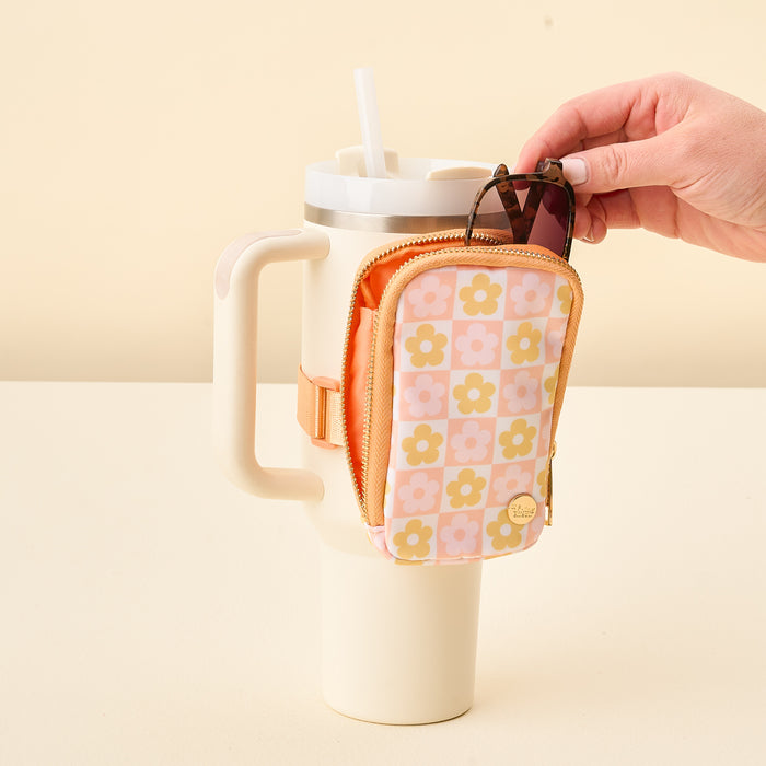 The Darling Effect’s Flower Check Peach Tumbler Fanny Pack, with a pink and yellow floral pattern, attaches to your cream tumbler with handle and straw—perfect for stashing sunglasses or essentials hands-free.