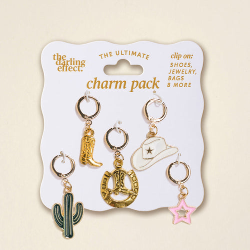 The Darling Effect's "Giddy Up The Ultimate Charm Pack" features five metal charms—a gold cowboy boot, cowgirl hat, heart rope, green cactus, and pink star—perfect for statement necklaces or scrunchie sets, beautifully displayed on a white card.