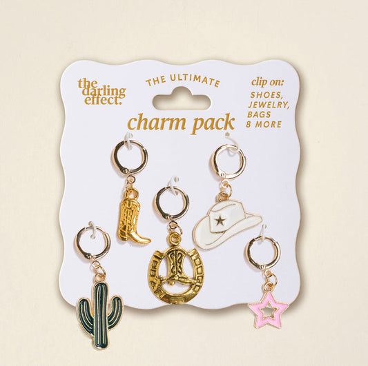 The Darling Effect's "Giddy Up The Ultimate Charm Pack" features five metal charms—a gold cowboy boot, cowgirl hat, heart rope, green cactus, and pink star—perfect for statement necklaces or scrunchie sets, beautifully displayed on a white card.