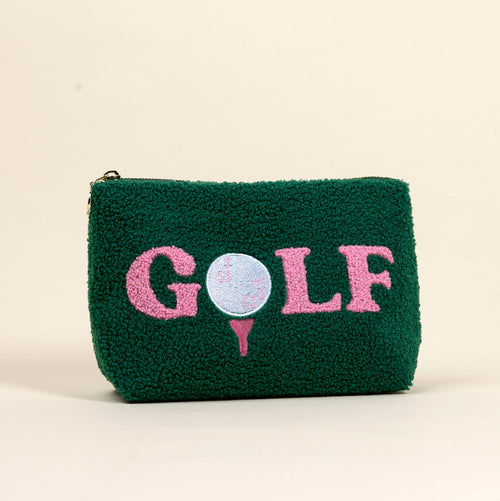The Darling Effect's Golf Teddy Pouch is a green textured sherpa pouch with "GOLF" in pink letters. The "O" is a blue golf ball on a pink tee, both embroidered. Background is plain off-white.
