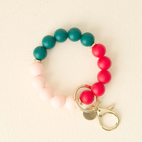 The Darling Effect’s Holly Jolly Hands-Free Keychain Wristlet features pink, red, and teal silicone beads with a gold clasp for a stylish, convenient way to carry your keys.