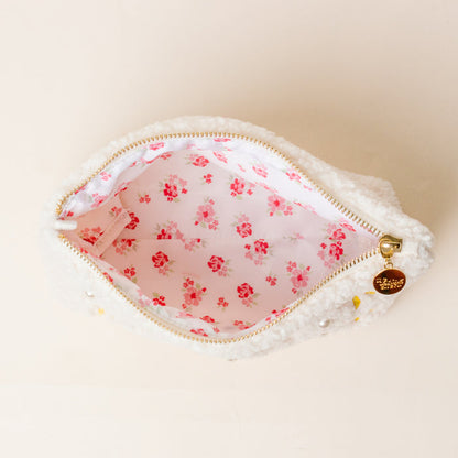 The Darling Effect's Kappa Alpha Theta Bows & Pearls Teddy Pouch is a small white sherpa pouch with embroidered bows, a gold charm zipper, and pink floral lining—perfect as a cute sorority gift.