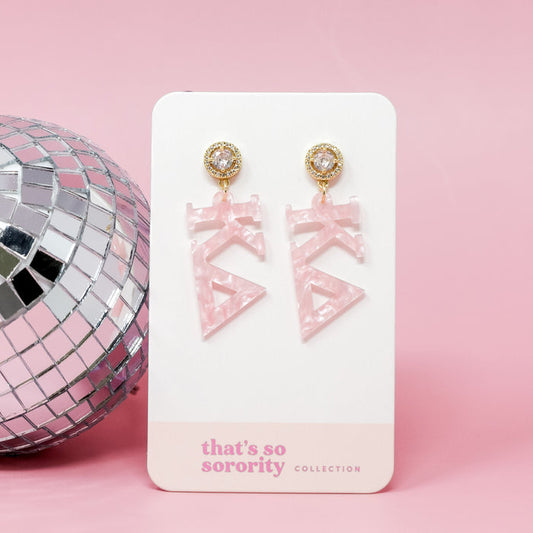 The Darling Effect's Kappa Delta Letter Pink Acrylic Earrings, adorned with rhinestones and a disco ball, come displayed on a "thats so sorority COLLECTION" card—perfect for sisterhood events or bid-day baskets!.