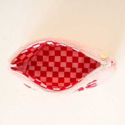 The Darling Effect's Mama Claus Teddy Pouch is an open pink zippered cosmetic pouch with a soft, fuzzy exterior and red-and-white checkerboard lining—a stylish travel essential for storing your must-haves.