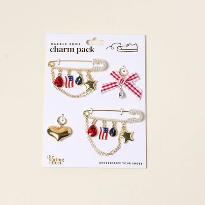 Add patriotic flair to your footwear with The Darling Effect’s Miss Americana Dazzle Shoe Charm Pack—featuring red, white, and blue sneaker charms, gold stars, and a gem-topped checkered bow. Perfect for American-themed style!.