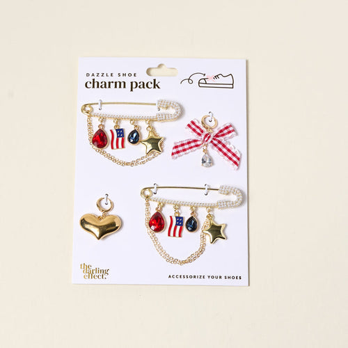 Add patriotic flair to your footwear with The Darling Effect’s Miss Americana Dazzle Shoe Charm Pack—featuring red, white, and blue sneaker charms, gold stars, and a gem-topped checkered bow. Perfect for American-themed style!.