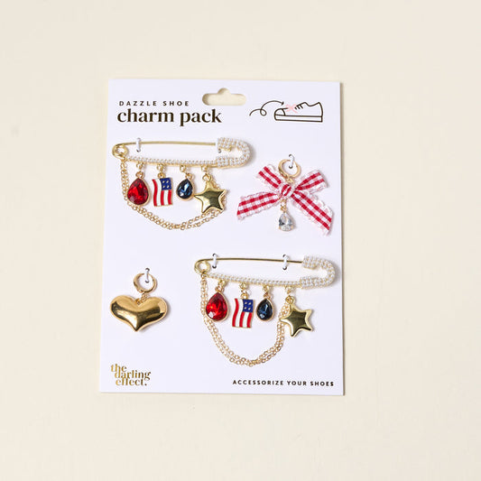Add patriotic flair to your footwear with The Darling Effect’s Miss Americana Dazzle Shoe Charm Pack—featuring red, white, and blue sneaker charms, gold stars, and a gem-topped checkered bow. Perfect for American-themed style!.