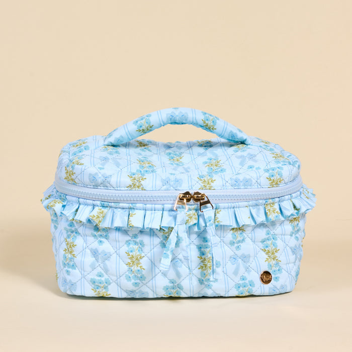 The Darling Effect's Oh So Fancy Blue Glam & Go Quilted Cosmetic Bag features a ruffled trim and gold zipper—perfect for stylishly organizing your essentials as a chic travel makeup bag.