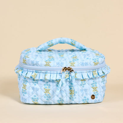 The Darling Effect's Oh So Fancy Blue Glam & Go Quilted Cosmetic Bag features a ruffled trim and gold zipper—perfect for stylishly organizing your essentials as a chic travel makeup bag.