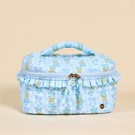 The Darling Effect's Oh So Fancy Blue Glam & Go Quilted Cosmetic Bag features a ruffled trim and gold zipper—perfect for stylishly organizing your essentials as a chic travel makeup bag.
