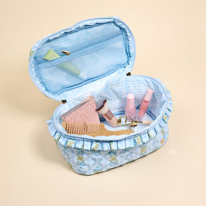 The Darling Effect’s Oh So Fancy Blue Glam & Go Quilted Cosmetic Bag features a floral design and opens to reveal a comb, pink hairbrush, makeup brush, two pink bottles, and cream tube—perfectly organized for travel.