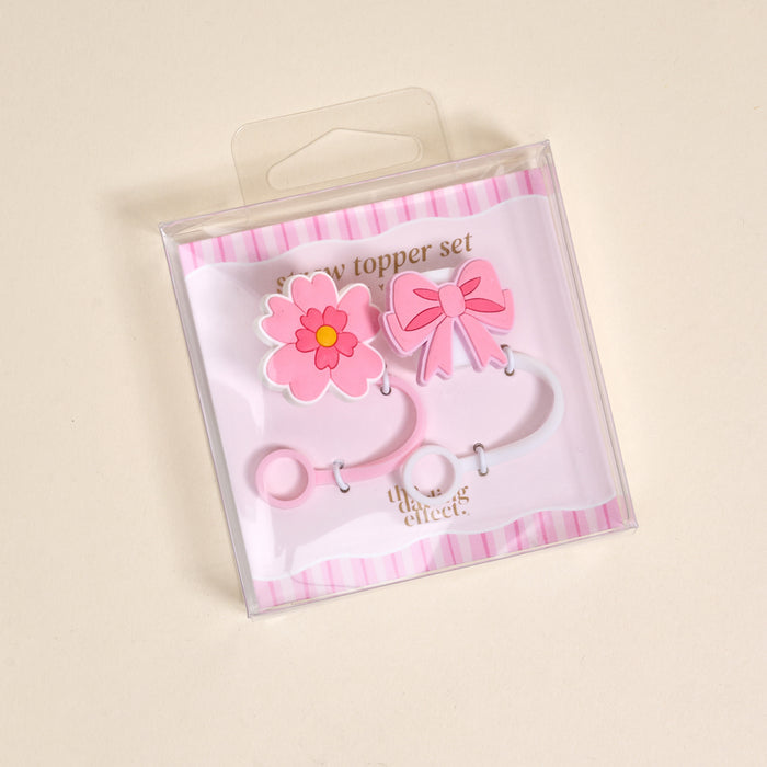 Pink flower and bow silicone straw toppers with pink and white bands, packaged in a clear plastic bag. These leak-resistant straw covers are adorable drinkware accessories for your favorite cups.