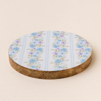 The Petal Parade Blue Wood Enamel Coaster by the-darling-effect features a white top with blue and purple floral patterns and vertical stripes, blending style and function to protect your table while adding charm to any space.