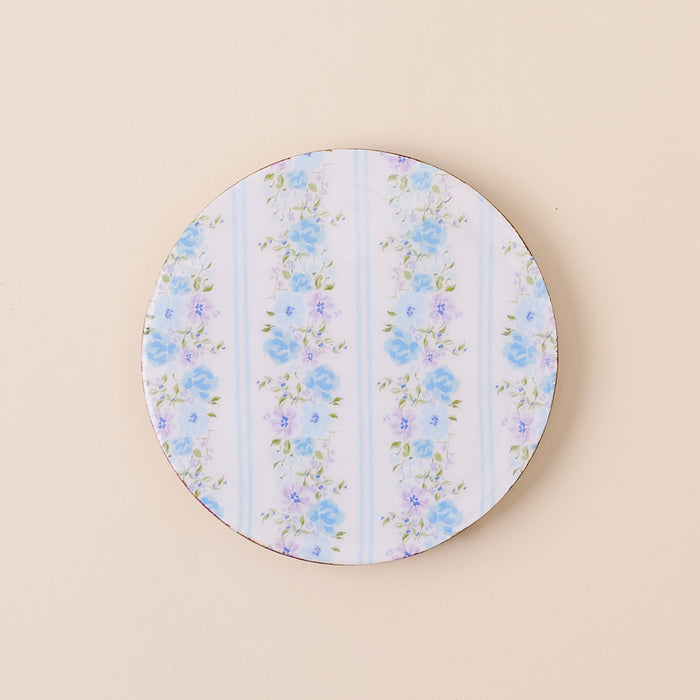 The-darling-effect’s Petal Parade Blue Wood Enamel Coaster features blue and purple floral designs with green leaves on white and light blue stripes—a stylish, durable addition to your coaster collection.