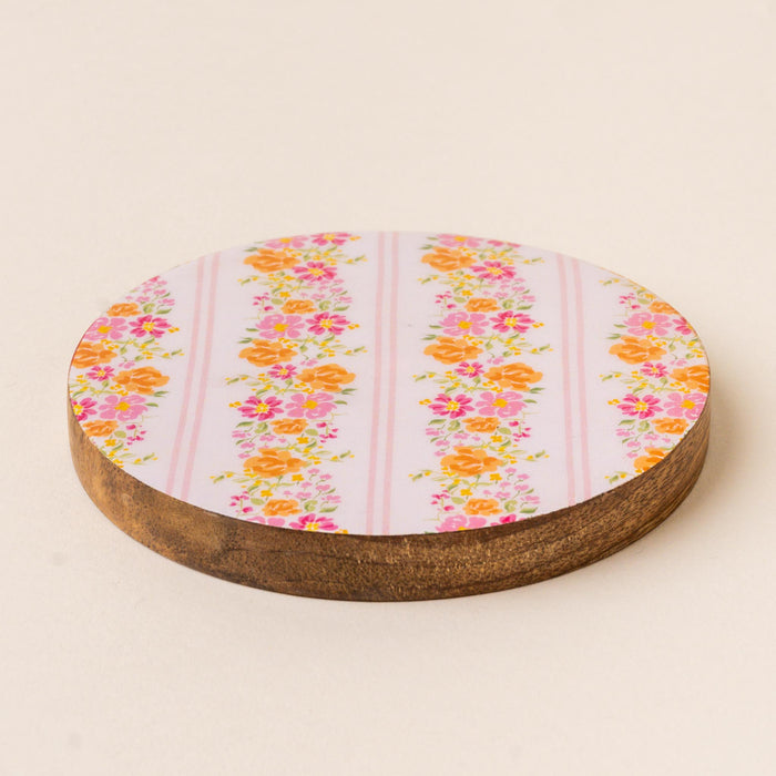 Add a pop of color to your table with the-darling-effect’s Petal Parade Pink Wood Enamel Coaster, featuring vertical stripes of pink and orange florals on light lavender with a dark brown wood edge—both stylish and functional.