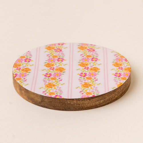 Add a pop of color to your table with the-darling-effect’s Petal Parade Pink Wood Enamel Coaster, featuring vertical stripes of pink and orange florals on light lavender with a dark brown wood edge—both stylish and functional.