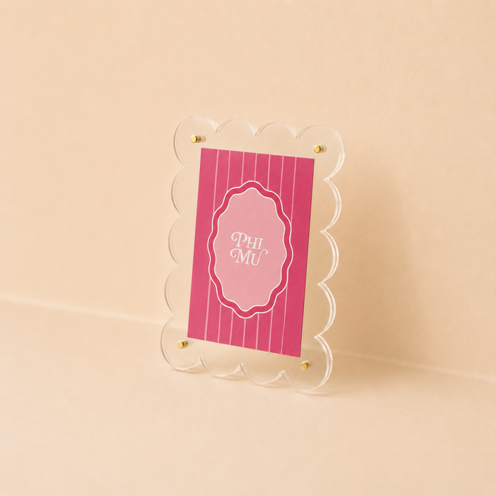 The Darling Effect's Phi Mu Mini Acrylic Picture Frame Magnet features scalloped edges and a pink, white-striped card with "PHI MU" in an ornate border—perfect for your mini fridge or displaying polaroids.