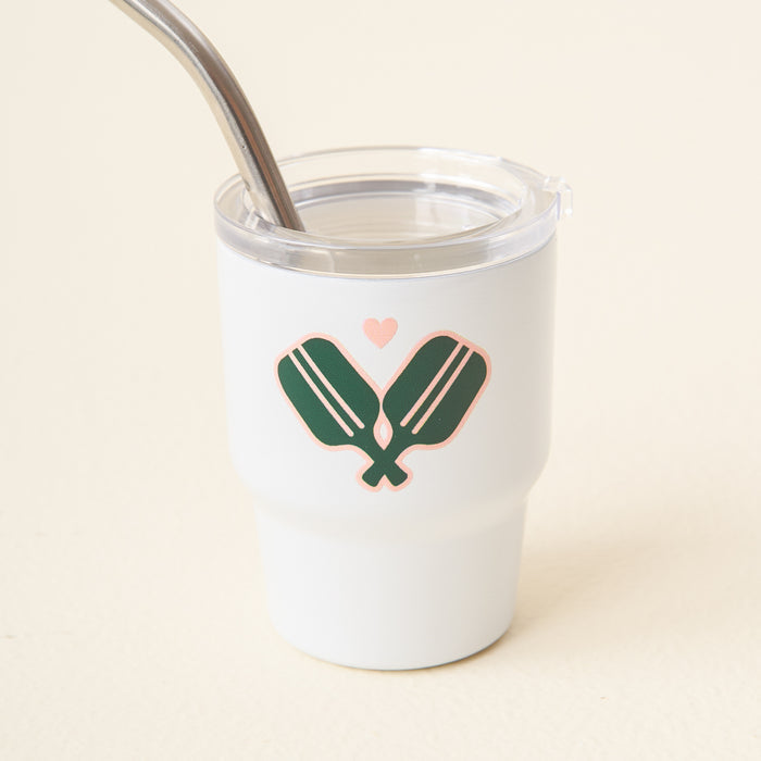 The Pickleball Paddles 2 oz Tiny Tumbler by the-darling-effect is a white insulated cup with a clear lid and metal straw, featuring two green pickleball paddles crossed with a pink heart—ideal for fans of cute mini tumblers.