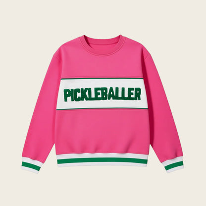 The Darling Effect’s Pickleballer Signature Crew is a bright pink sweatshirt with white and green sleeve and hem stripes, soft fabric, and a bold green PICKLEBALLER print on a white chest panel.