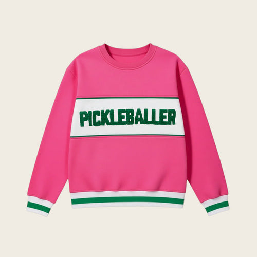 The Darling Effect’s Pickleballer Signature Crew is a bright pink sweatshirt with white and green sleeve and hem stripes, soft fabric, and a bold green PICKLEBALLER print on a white chest panel.