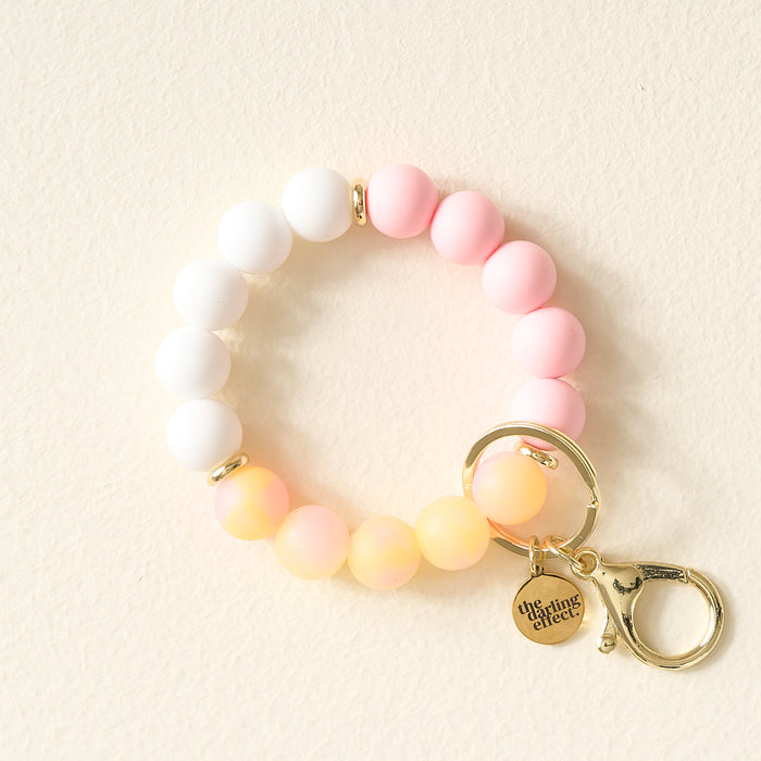 The Darling Effect's Pink Lemonade Hands-Free Keychain Wristlet features pastel ombre beads, a gold clasp, and a practical silicone bracelet for easy, stylish key holding.