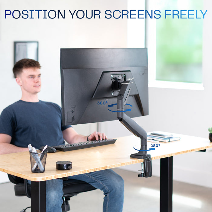 Person using a adjustable monitor stand at a desk in bright office space.