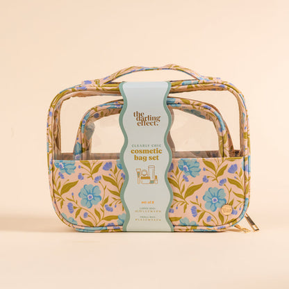 The Darling Effect’s Poppin' Petals Aqua Clearly Chic Cosmetic Bag Set features two nested clear bags with blue and purple floral panels on cream and a branded label.