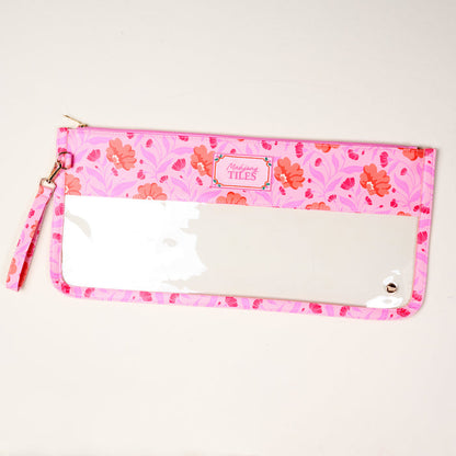The Darling Effect's Poppin' Petals Hot Pink Mahjong Tile Keeper Pouch features a pink floral pattern, clear front panel, and wrist strap—ideal for organizing your Mahjong essentials in style. "Marilyns TILES" label at top center. Displayed on light surface.