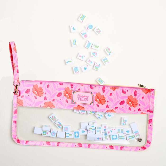 The Darling Effect's Poppin' Petals Hot Pink Mahjong Tile Keeper Pouch, featuring a transparent section, holds small Mahjong tiles—some scattered on a light surface above the stylish organizer.