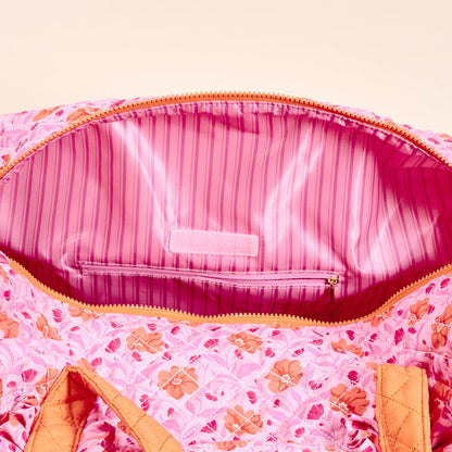 The Darling Effect’s Poppin' Petals Hot Pink On-the-Go Quilted Weekender Bag features a floral print, orange trim, pink striped lining, and brand label—a spacious, stylish option for travel.
