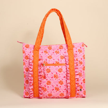 The Darling Effect's Poppin' Petals Hot Pink The Everyday Quilted Tote Bag features orange floral patterns, ruffled trim, a front zip pocket, and quilted handles—ideal as an everyday or stylish travel tote.