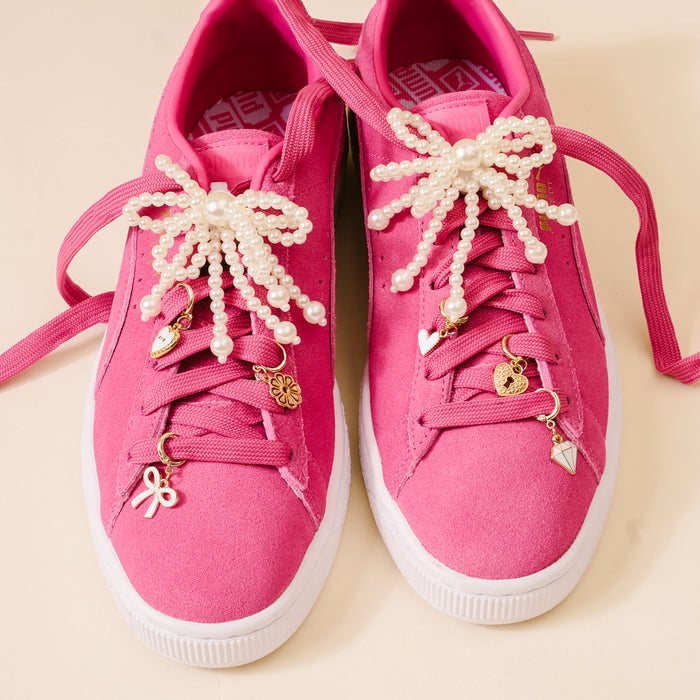 Add playful flair to your shoes with the-darling-effect’s Pretty in Pearl Dazzle Shoe Charm Pack—featuring gold and white bow, heart, flower & diamond charms plus pearl and bead lace decorations for bright pink sneakers.