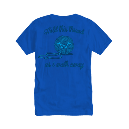 A vibrant blue cotton t-shirt featuring a teal embroidered design of a yarn ball with the text ’hold this thread as i walk away’ above and below it.