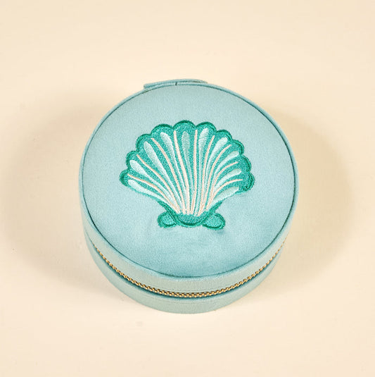 The Darling Effect's Seashell Round Velvet Jewelry Case features light blue velvet, a green embroidered seashell on the lid, and a gold zipper—an elegant ring holder shown against a plain beige background.