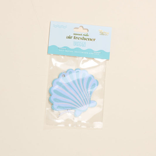 The Darling Effect's Seashell Sweet Ride Car Air Freshener offers a unique salt water, driftwood, and lily scent. Housed in clear packaging with blue and white accents, it guarantees a long-lasting ocean-inspired aroma for your drive.