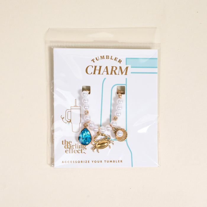 Add coastal flair to your tumbler with The Darling Effect’s Seaside Sparkle Tumbler Charm, featuring a blue gem, gold crab, and gold seashell—an eye-catching accessory for your handle.