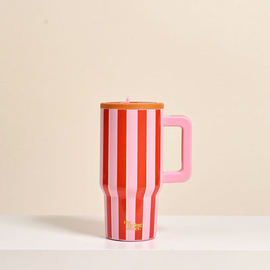 The Darling Effect Sicily Stripes Pink 20 oz Lifestyle Flip Straw Tumbler, featuring vertical red and white stripes, a pink handle, and brown lid, sits on a white surface. This insulated stainless steel tumbler keeps drinks perfectly hot or cold.