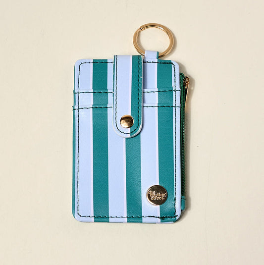 The Darling Effect Sicily Stripes Teal Keychain Wallet features vertical teal and white stripes, a snap button strap, gold keyring, zippered coin holder, and side zipper pocket—shown on a light beige background.