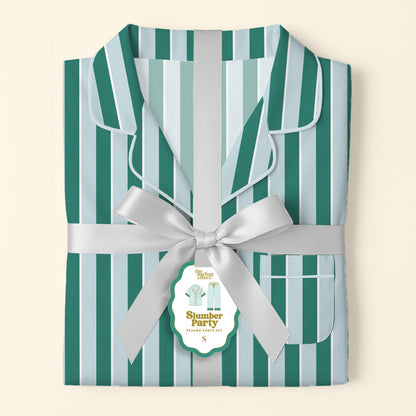 The Darling Effect’s Sicily Stripes Teal Slumber Party Pajama Pants Set, featuring teal and light blue stripes and crafted from ultra-soft fabric, is tied with a silver ribbon and a “Slumber Party Pajama Set” tag on a pale background.