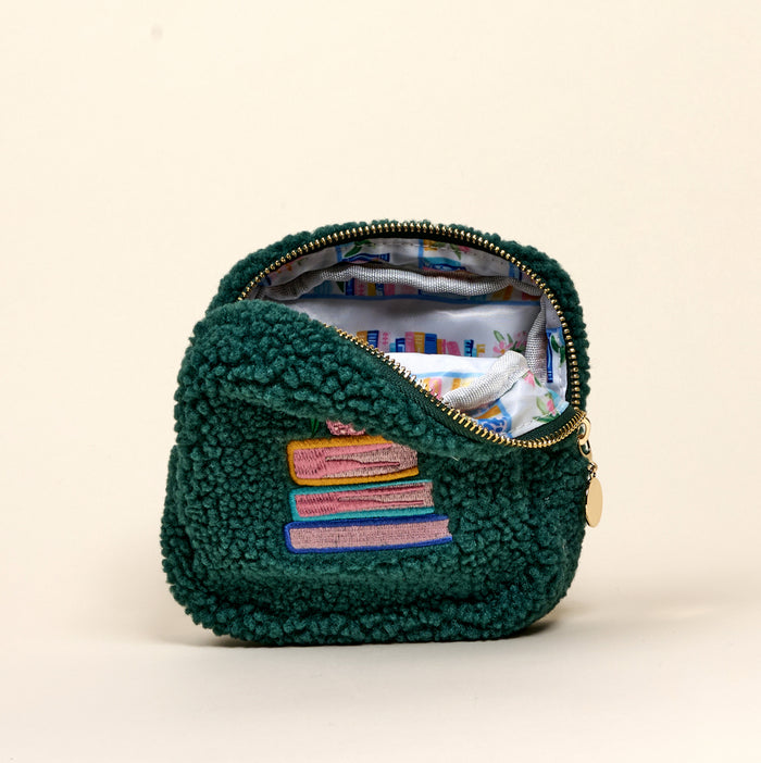 The Darling Effect’s Square Book Nook Teddy Pouch is small, green, and textured, with pastel books embroidered outside and a colorful book-themed lining inside.