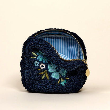 The Square Dainty Floral Navy Teddy Pouch by the-darling-effect is a small, textured navy pouch with floral embroidery, a gold zipper, and blue-and-white striped lining.