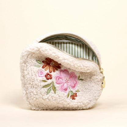 The Square Dainty Floral Pink Teddy Pouch by the-darling-effect is a small white sherpa pouch with a gold zipper, embroidered pink/red flowers and green leaves, plus a green and white striped lining.