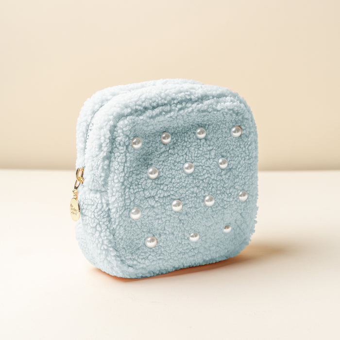 The Square Pearl Blue Teddy Pouch by the-darling-effect features a light blue, square design with soft sherpa fabric, pearl-like beads on the front, and a gold zipper with a round charm.