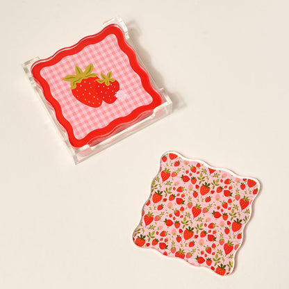 The Darling Effect’s Strawberry Fields Table Talk Acrylic Coaster Set includes two square coasters—one with a pink gingham and large strawberry, the other with smaller strawberries and flowers—perfect for adding bold style to your table.