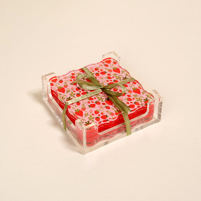 The Darling Effect’s Strawberry Fields Table Talk Acrylic Coaster Set features floral coasters in a clear acrylic holder, tied with a green ribbon—adding charming table décor to any plain light background.