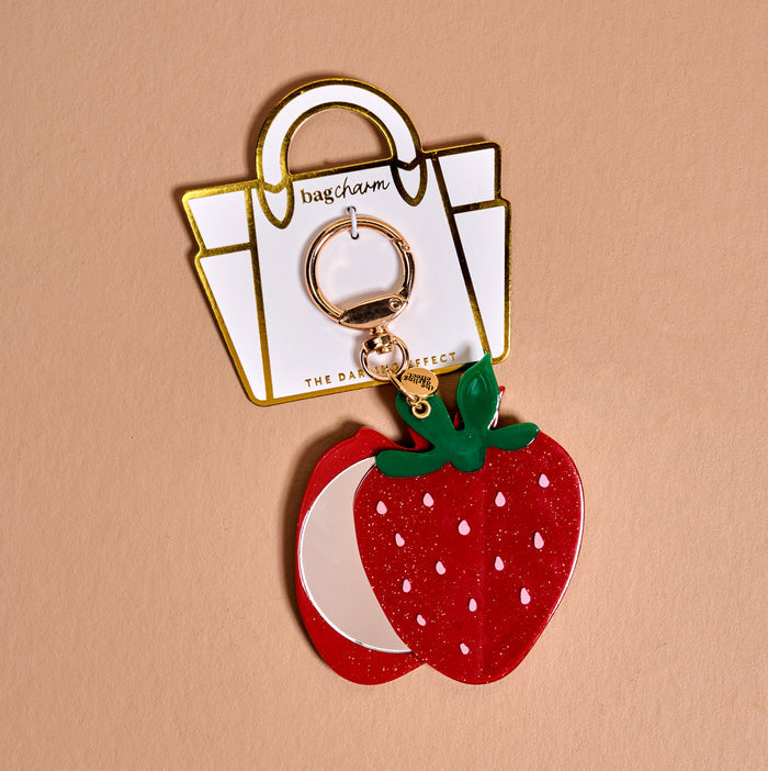 The Darling Effect's Strawberry Mini Mirror Bag Charm is a cute bag accessory, featuring a strawberry-shaped acrylic mirror on a gold keyring, presented with a white display card.