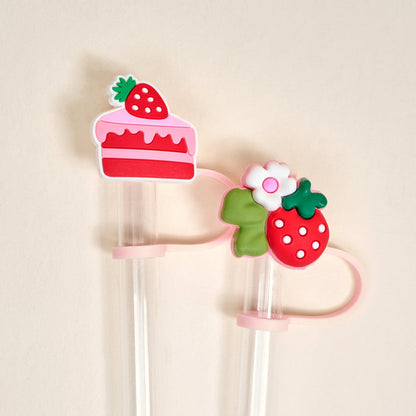 The Darling Effect’s Strawberry Shortcake Straw Topper Set includes two clear plastic straws with leak-resistant silicone toppers—a strawberry cake slice and a strawberry with leaves and flower—perfect sweet drinkware accessories.