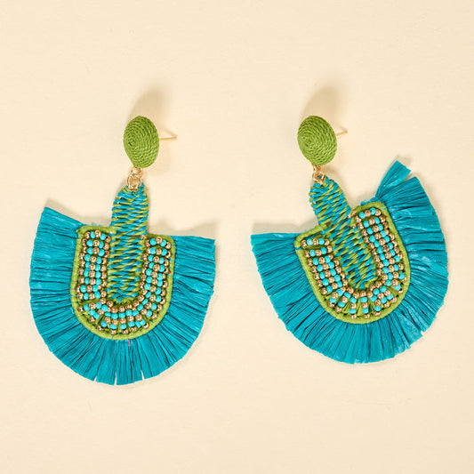 The Darling Effect's Teal Fringe Earrings feature green oval studs, blue and green beaded semicircles, and bright blue fan-shaped fringe—lightweight statement boho earrings perfect for everyday wear on a beige background.