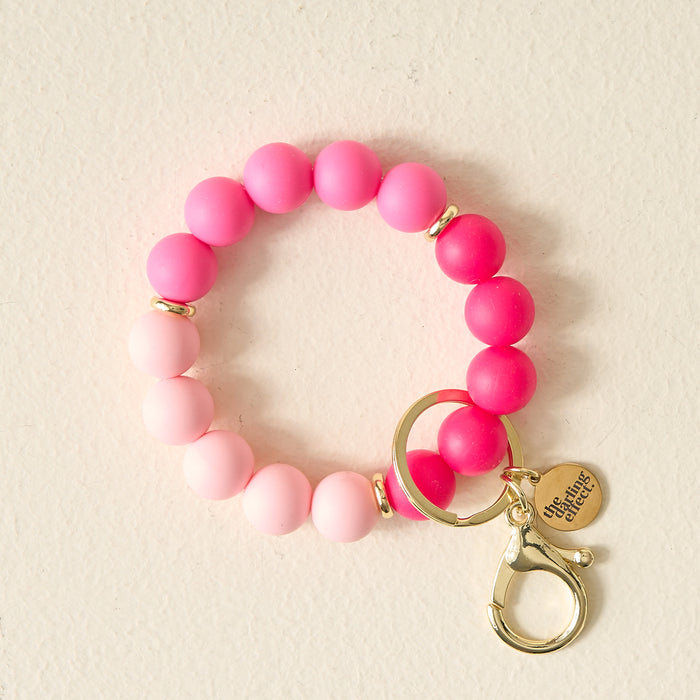 The Darling Effect Tickled Pink Hands-Free Keychain Wristlet features pink and red gradient beads, gold rings, a lobster clasp key holder, and a "You got this!" charm—all for hands-free style.
